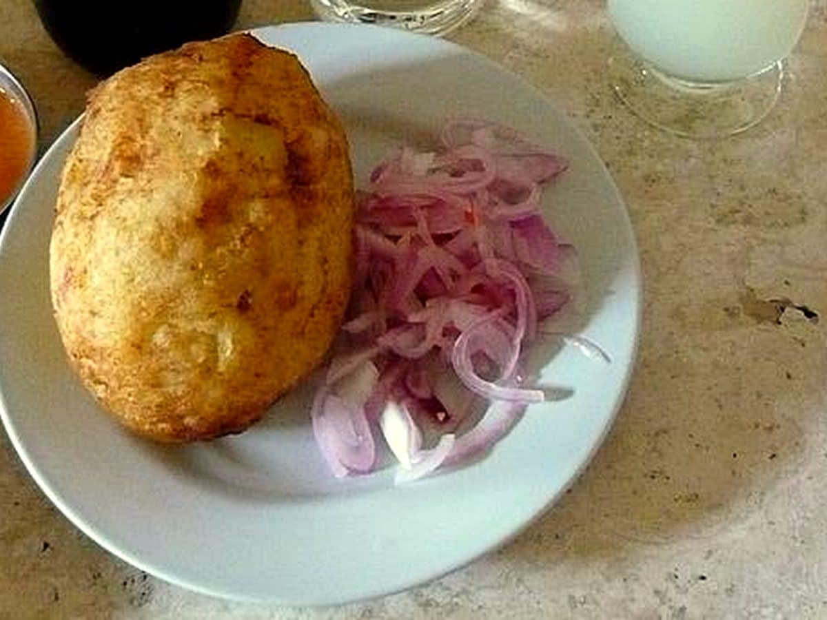 Papa rellena peruana dorada con salsa criolla de cebolla