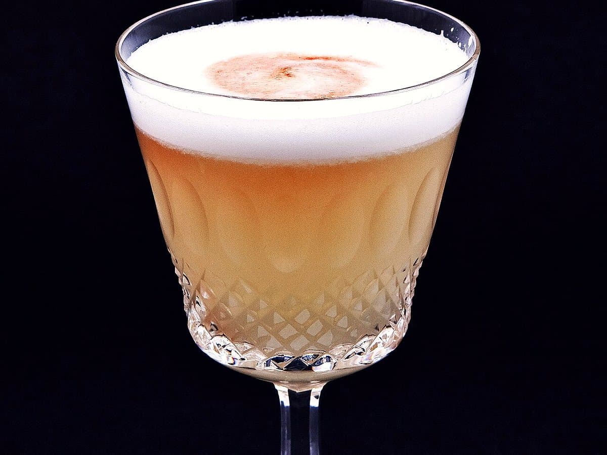 Pisco sour clásico con su espuma y gotas de amargo de angostura
